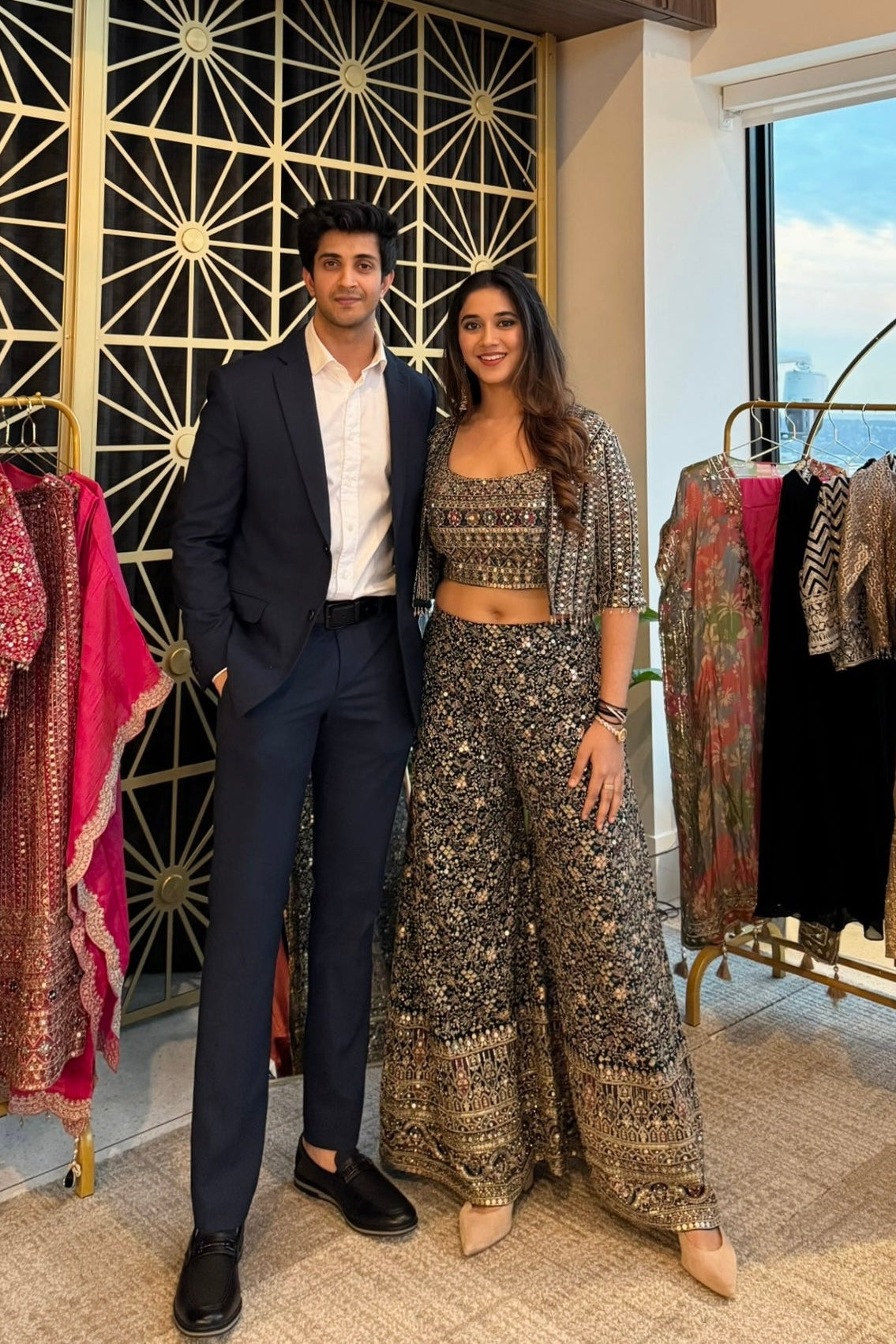 Man and woman posing in a clothing store with fashion items around