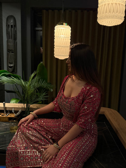 Woman in a red patterned dress sitting in a dimly lit room with hanging lights.